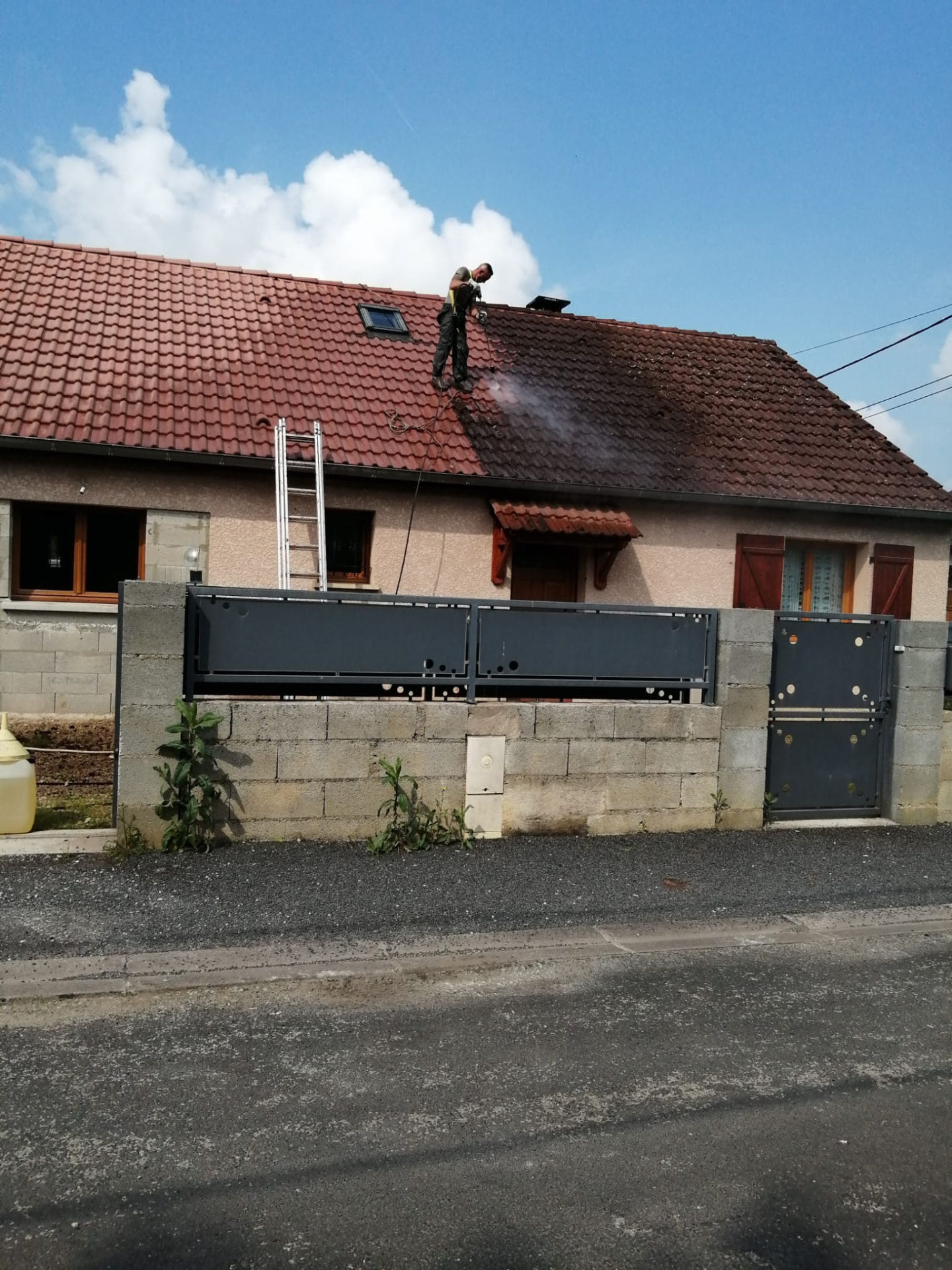 Couvreur en cours de démoussage sur une toiture